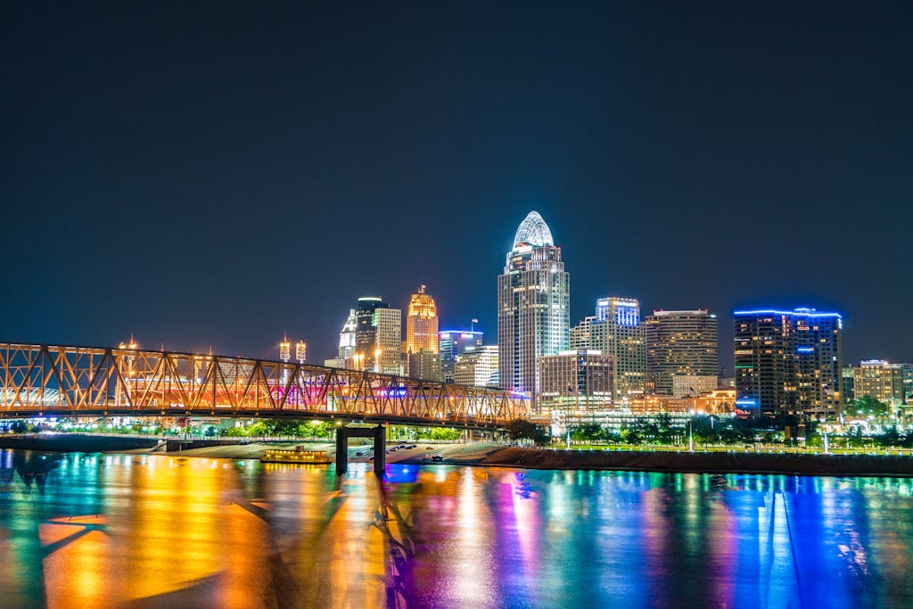 Captivating view of Cincinnati skyline with bridge reflections on Ohio River at night.